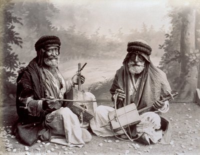 Porträt von zwei arabischen Musikern in bescheidener ethnischer Kleidung. Die älteren Männer posieren im Studio, auf dem Boden sitzend. Hinter ihnen ist ein Hintergrund mit einer bewaldeten Landschaft von Félix Bonfils
