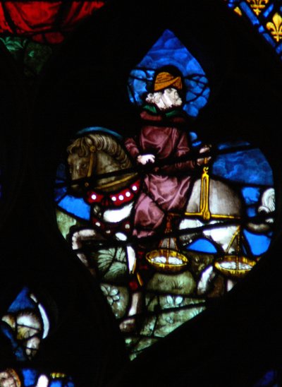 Das westliche Rosenfenster zeigt eine Szene aus dem Buch der Offenbarung: Ein Reiter (sein Pferd nicht schwarz wie im Text) trägt die Waage, um Weizen und Gerste zu messen (6:5). von French School