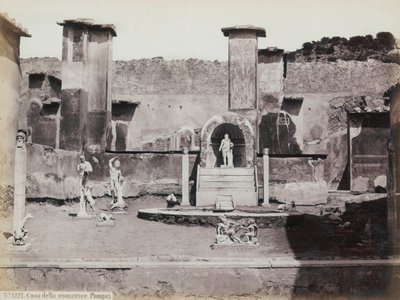 Teilansicht des erhöhten Gartens des Hauses des Marcus Lucretius in Pompeji, dekoriert mit Marmorstatuen und Hermen. In der Mitte ein Brunnen mit einer Nische. Im Hintergrund Fragmente von Wandmalereien von Giorgio Sommer