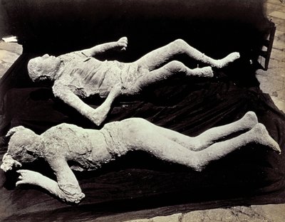 Zwei Abgüsse von menschlichen Figuren aus den Ausgrabungen von Pompeji. Die Exponate wurden auf schwarzem Tuch platziert, um sie zu fotografieren von Giorgio Sommer
