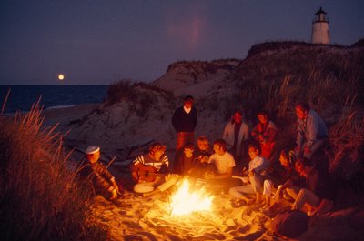 Freunde versammeln sich um ein Sommerlagerfeuer am Great Point Leuchtturm. Nantucket Island von James L Stanfield