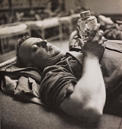 Militärischer Genesender betrachtet eine kleine Flasche mit einer chemischen Zubereitung von Luigi Leoni