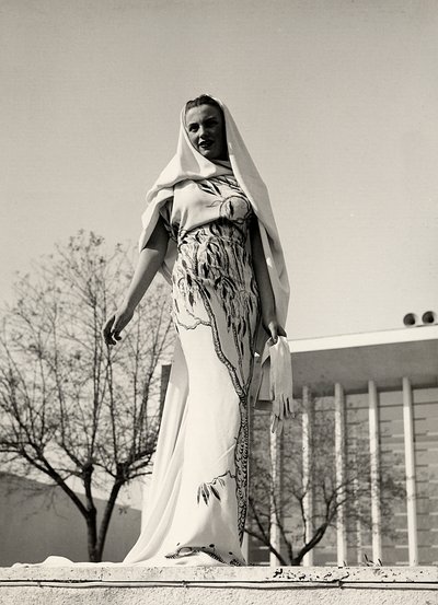 Modell in einem Abendkleid aus Blumenstoff, kreiert vom Modehaus "Lamma". Das Kleid wird mit einem langen Schleier ergänzt. von Luis Bogino