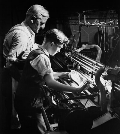 Ein Meister bildet einen jungen Lehrling im Maschinenstricken aus, Lyle und Scott, Hawick von Unbekannt