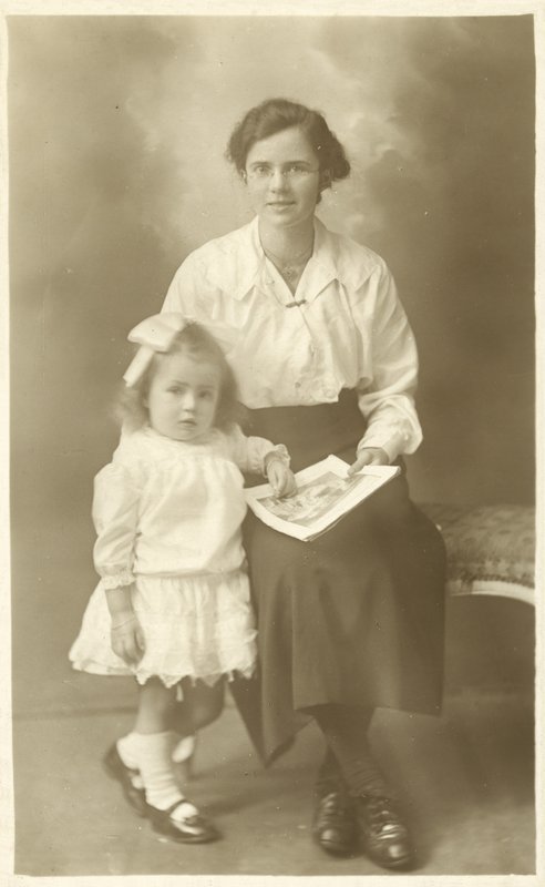 Hübsches Mädchen, Mutter oder Gouvernante, zeigt einem kleinen Kind Fotos von English Photographer