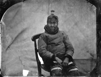 Eine ältere Inuk-Frau, die auf einem Stuhl sitzt
