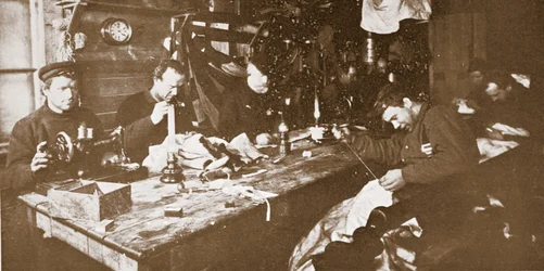In der Hütte während des Mittwinters, die Männer nähen Pelze für Kleidung, die im Frühling beim Schlittenfahren verwendet werden soll, veröffentlicht in London 1907