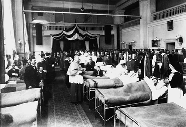 Dekorierter Salon in einem Krankenhaus mit Kriegsverwundeten während eines priesterlichen Besuchs (s/w Foto)