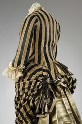 Abendkleid, ca.1884 (hintere schräge Teilansicht). Seidensatin und geschnittener Samt, Spitze, Seidenfadenquasten und Fransen. Charles Frederick Worth, Frankreich.