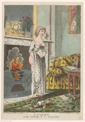 Frau wärmt sich am Herd, ein Buch in der Hand