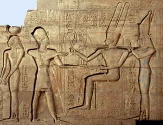 Ägyptische Antiquität: Relief mit der Darstellung des Pharaos Ramses II. vor zwei Gottheiten der thebanischen Triade, Amun und Mut; dem Pharao Ramses II. (1279-1213 v. Chr.) gewidmeter Totentempel, Stätte des Ramesseums (Ramesseum) in Luxor, Ägypten.