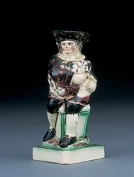 Dick Whittington Krug, geformt aus einem hochlehnigen Stuhl, hält seine Katze, gesprenkelt in brauner, grüner und schwarzer Kleidung, ein geformtes Schild an seiner Seite, ca. 1790