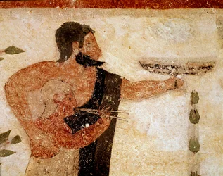 Ein bärtiger Mann präsentiert eine Tasse, neben ihm ein Musiker (Detail)