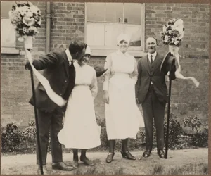 Zwei Männer mit Tutti-Stangen, stehend mit zwei Frauen während des Hocktide-Festivals in Hungerford
