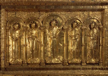 Vor dem Altar der Kathedrale von Basel. Um den sitzenden Christus, die drei Erzengel (Michael, Gabriel und Raphael) und der heilige Benedikt von Nursia, und zu seinen Füßen, der Kaiser Heinrich II., genannt der Heilige (973-1024) und die Kaiserin Kunigunde