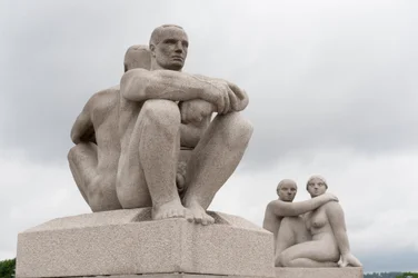 Skulpturen zweier nackter Männer, die Rücken an Rücken sitzen; dahinter eine Skulptur zweier Frauen im Frognerpark, Oslo, Norwegen