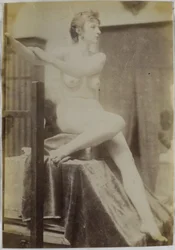 Studie eines weiblichen Aktmodells, sitzend auf einem Podium neben einer Staffelei und schräg von vorne gesehen, im Atelier von Jacques de Lalaing, Vorstudie für das Grabdenkmal Fernand Scribe auf dem Friedhof von Gent