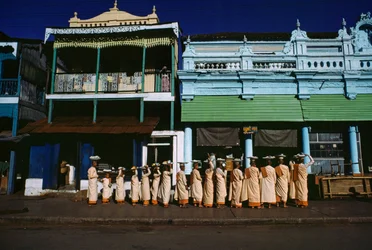 Buddhistische Nonnen verschiedenen Alters marschieren auf dem Bürgersteig und bitten um Almosen. Maymyo, Burma.