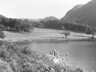 Eine Familie am Rand des Sees angelt und schaut ins Wasser