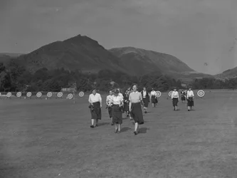 Eine Ansicht von Bogenschützinnen, möglicherweise Teil eines Wettbewerbs, mit Hügeln im Hintergrund
