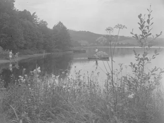 Mann angelt in einem Boot auf Esthwaite Water und zwei Mädchen am Ufer
