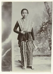 Studio-Porträt einer jungen javanischen Frau in einem Sarong mit Batikmuster und einem Hemd mit Karomuster