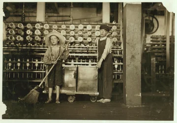 12-jähriger Doffer Ronald Webb und 7-jähriger Frank Robinson, Sohn des Cardroom-Bosses, der fegt und dofft (leert volle Spulen) in den Roanoke Cotton Mills, Virginia, 1911