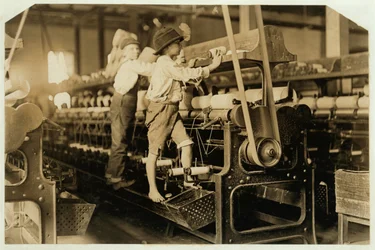 Kleine Jungen klettern auf ein Spinngestell, um gerissene Fäden zu flicken und leere Spulen auszutauschen, Bibb Mill, Macon, Georgia, 1909