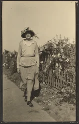 [Frau geht entlang eines Zauns mit Blumen]