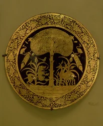 Teller mit einem Rand aus stilisierten Blumen, der eine Szene mit exotischen Tieren unter einem ausladenden Baum umgibt (vergoldete Bronze)