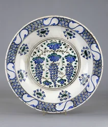 Ein Iznik-Keramikteller, mit einem zentralen Rundel, das drei Traubenbündel und Weinblätter darstellt, ca. 1570