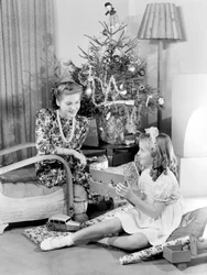Frau und Mädchen betrachten Weihnachtsgeschenke, ca. 1950