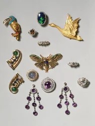 Auswahl an Schmuckstücken: Amethyst- und Diamant-Chandelier-Ohrringe; Brosche mit einem Sternsaphir im Cabochonschliff und Diamanten; Ring mit schwarzem Opal; Amethyst- und Diamantbrosche oder -anhänger; goldene Clipbrosche in Form eines fliegenden