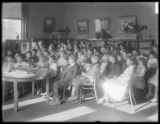 Kinder sitzen und hören im Lesesaal einer nicht identifizierten Filiale der Queens Borough Public Library, um 1910