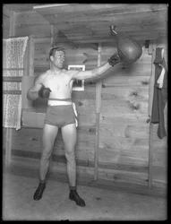 Englischer Boxer William Thomas Wells (Bombardier Billy Wells), posierend in Trainingskleidung mit einem Speedbag, ca. 1911