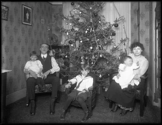 Informelles Gruppenporträt einer unbekannten Familie in ihrer Wohnung vor einem Weihnachtsbaum, New York City, ca. 1915-16