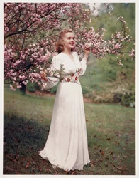 Frau, die ein Kleid in der Nähe von Blüten modelliert, ca. 1940er